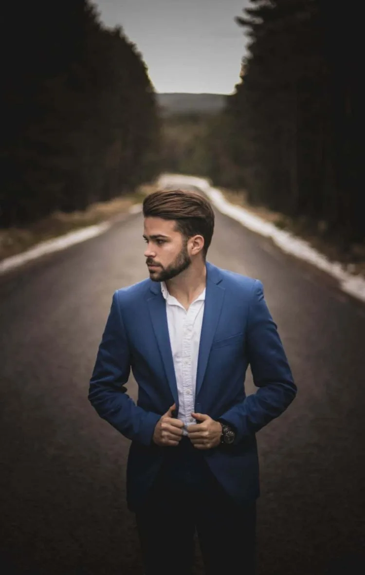 man with blue suit standing on road