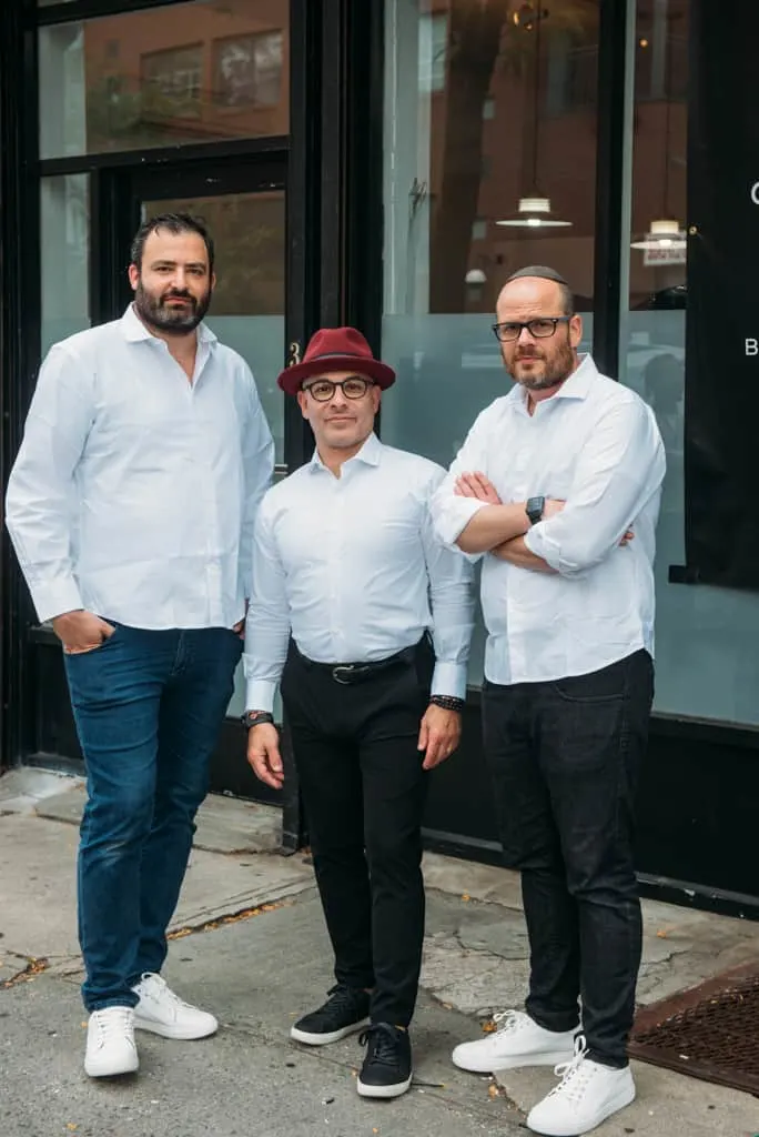 A tall man and 2 short men wearing a white long sleeve polo