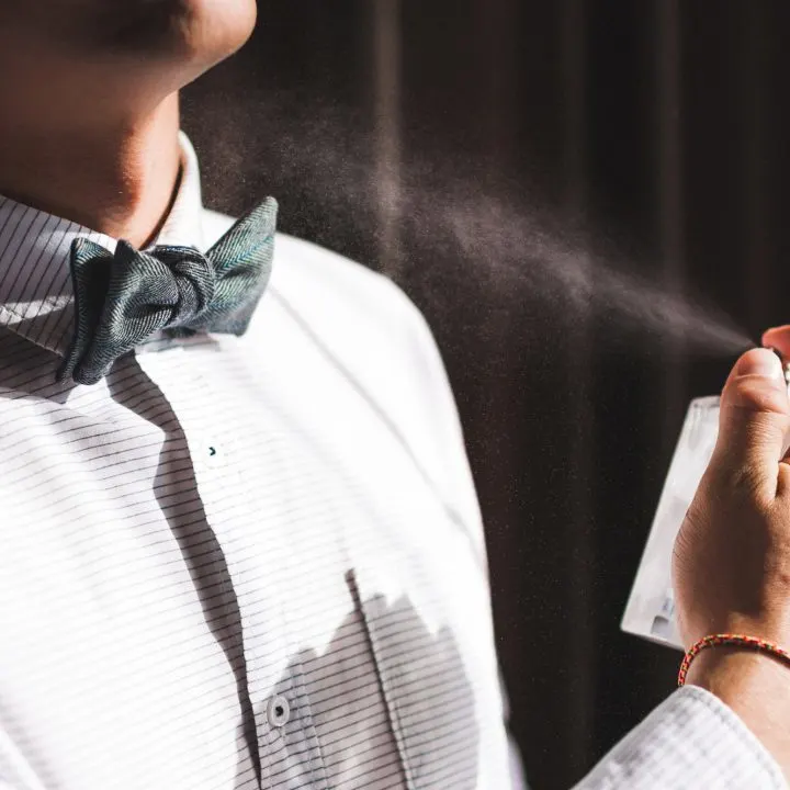 Man applies perfume and smells fragrance