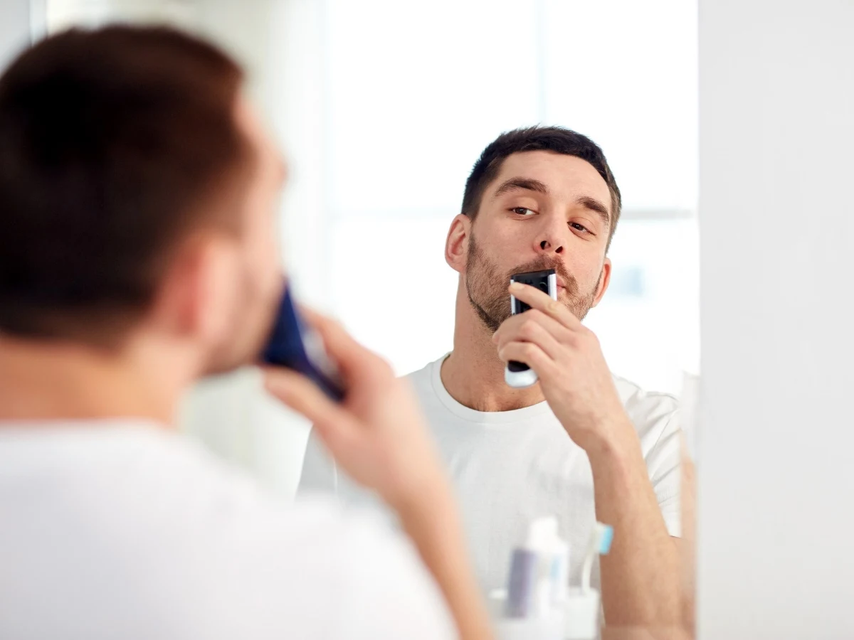 Handsome man trimming and shaping his mustache